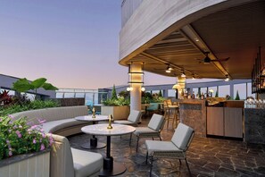 A rooftop bar with seating, a bar area, and a view of the cityscape. - Sheraton Vinh (Vinh)