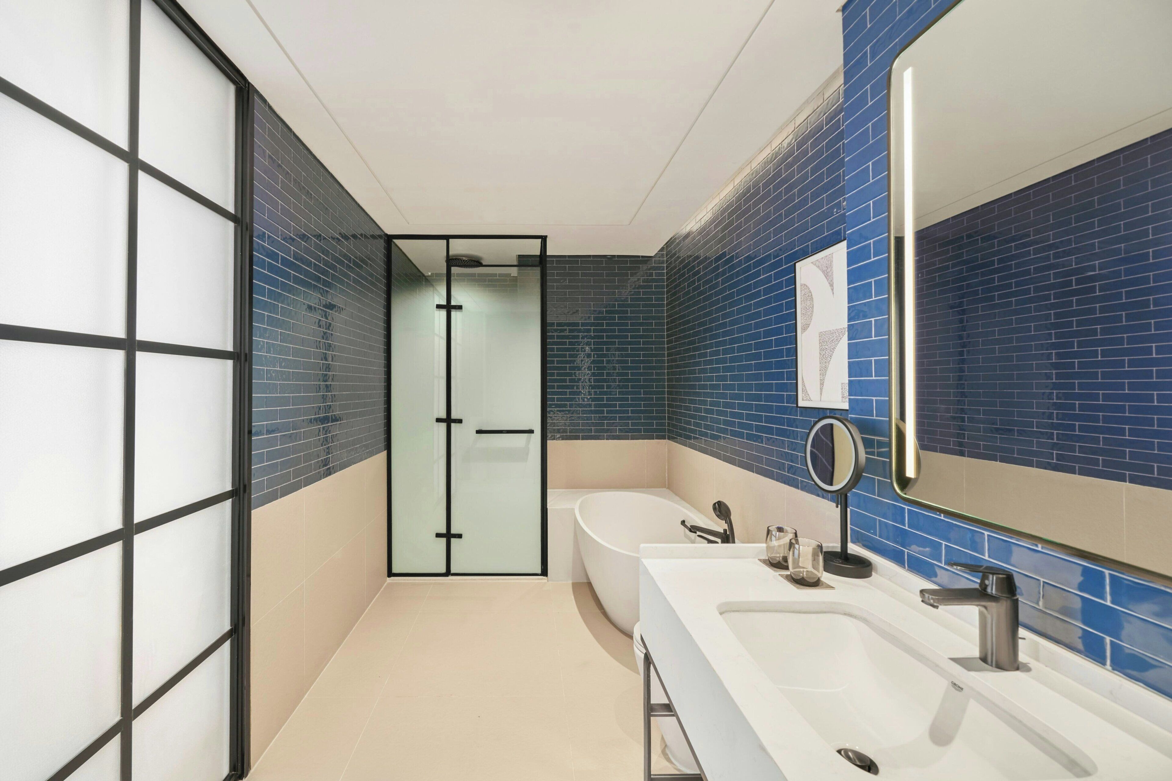 A modern bathroom with a large bathtub, two sinks, a glass shower enclosure, and a mirror.
