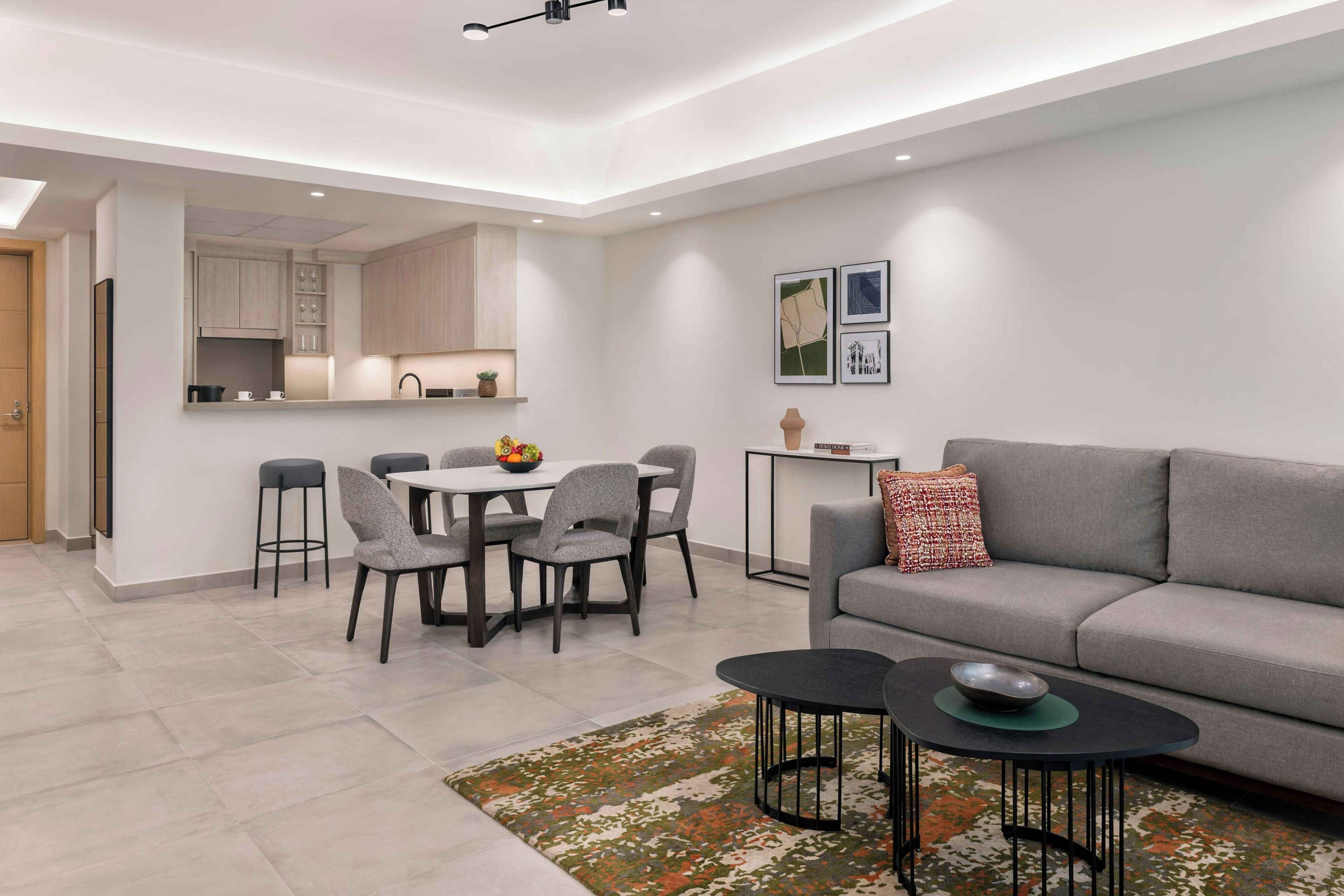 Una sala de estar moderna con un sofá gris, una mesa de centro y un comedor con sillas y una mesa.