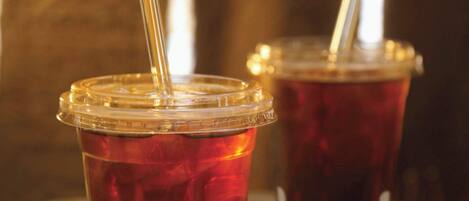 Two plastic cups with straws on a wooden surface.