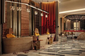 A modern lobby with a reception desk, seating areas, and a bar.