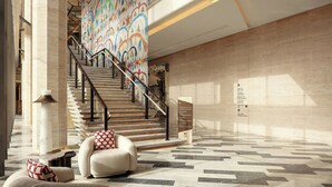 A modern lobby with a staircase, a seating area, and a wall with a colorful mural. - W Riyadh - KAFD (Riyadh)