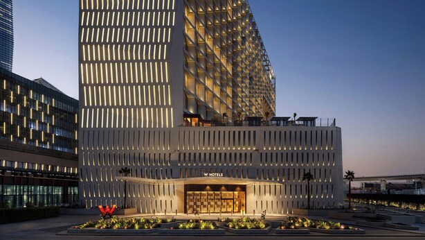 A modern hotel with a prominent 'W Hotels' sign, a unique facade with vertical lighting, and a landscaped entrance area. - W Riyadh - KAFD (Riyadh)