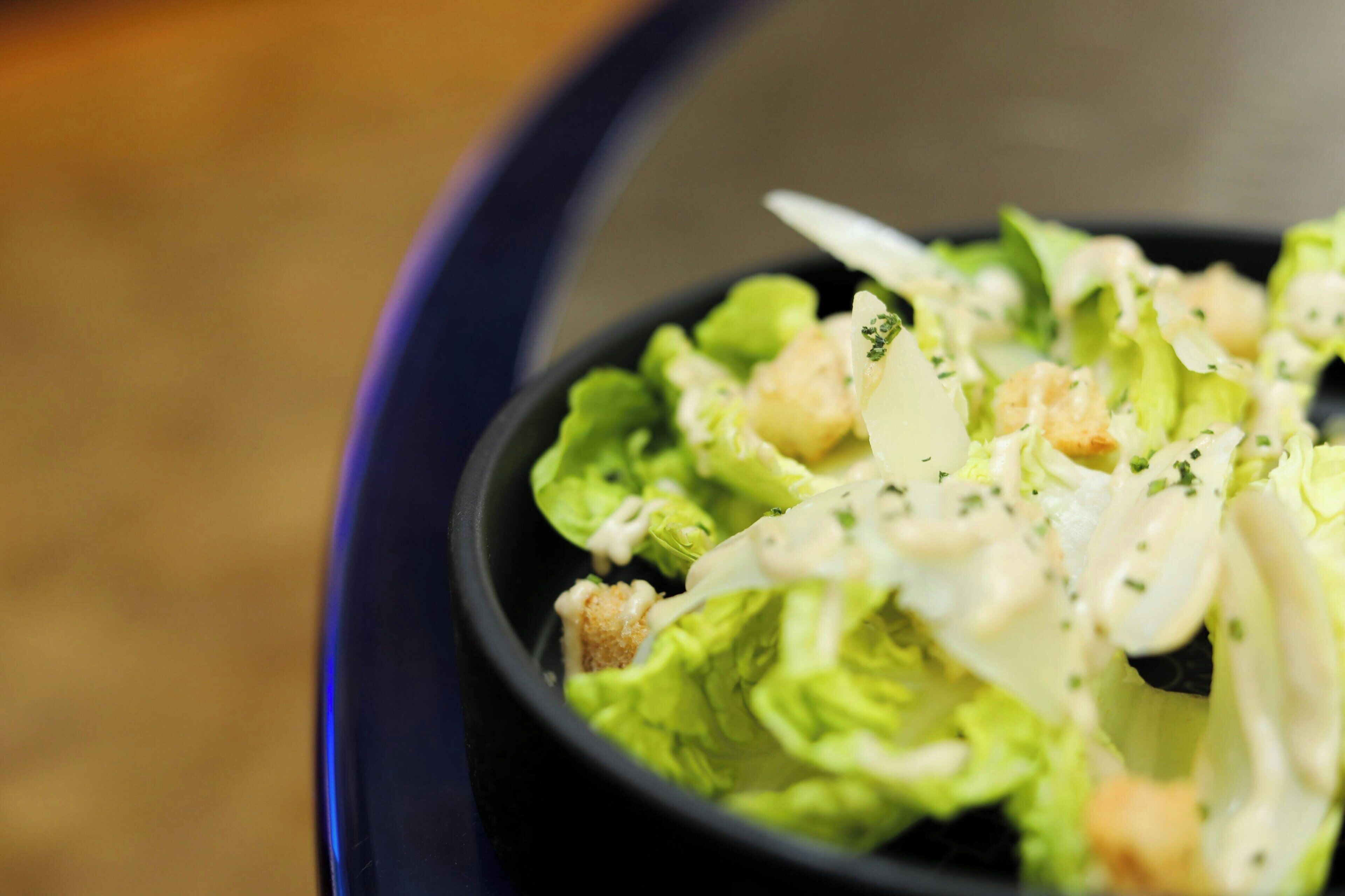 Een saladekom met croutons en een romige dressing.
