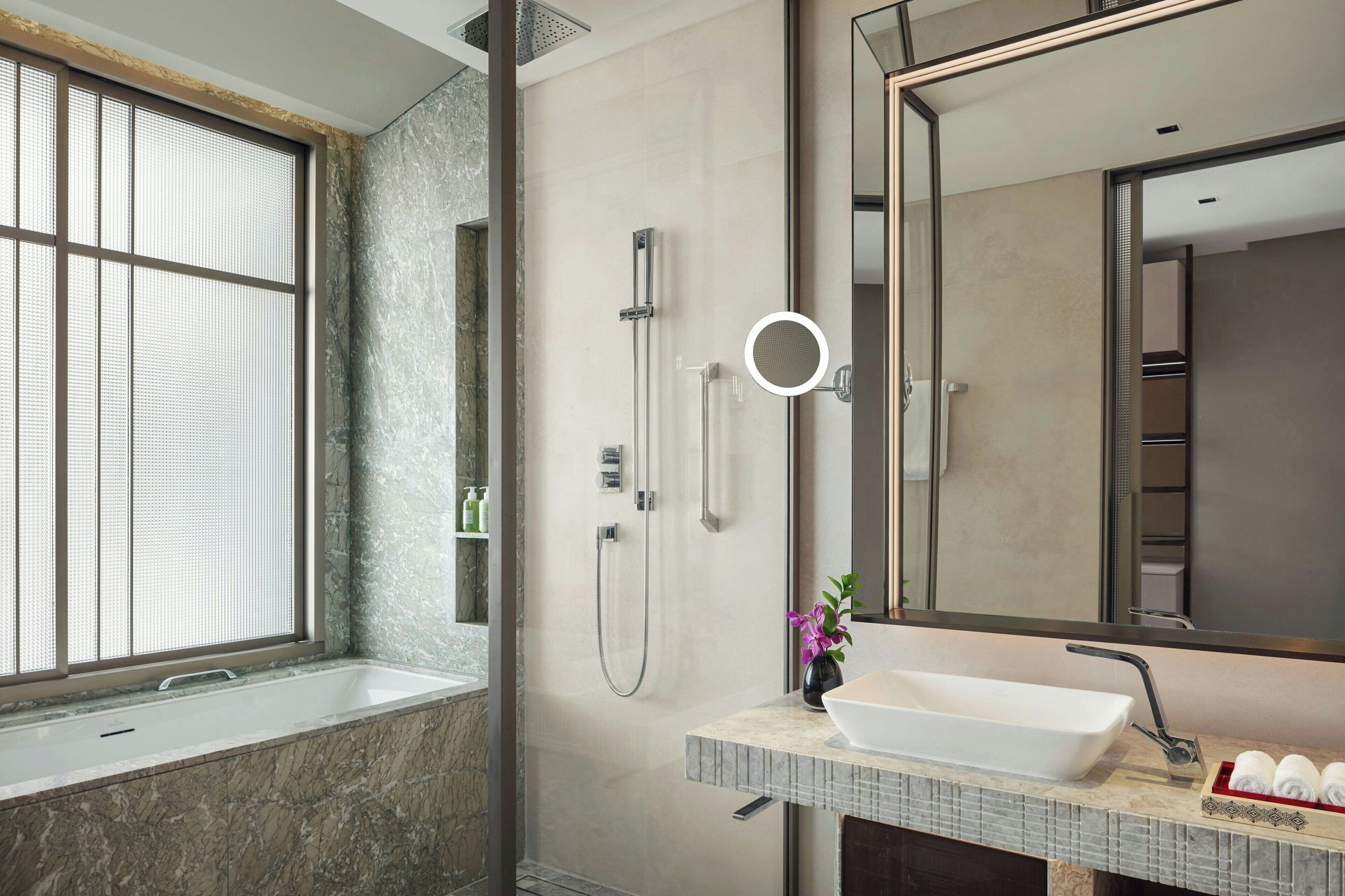 A modern bathroom with a large window, a walk-in shower, a vanity with a basin, and a mirror.