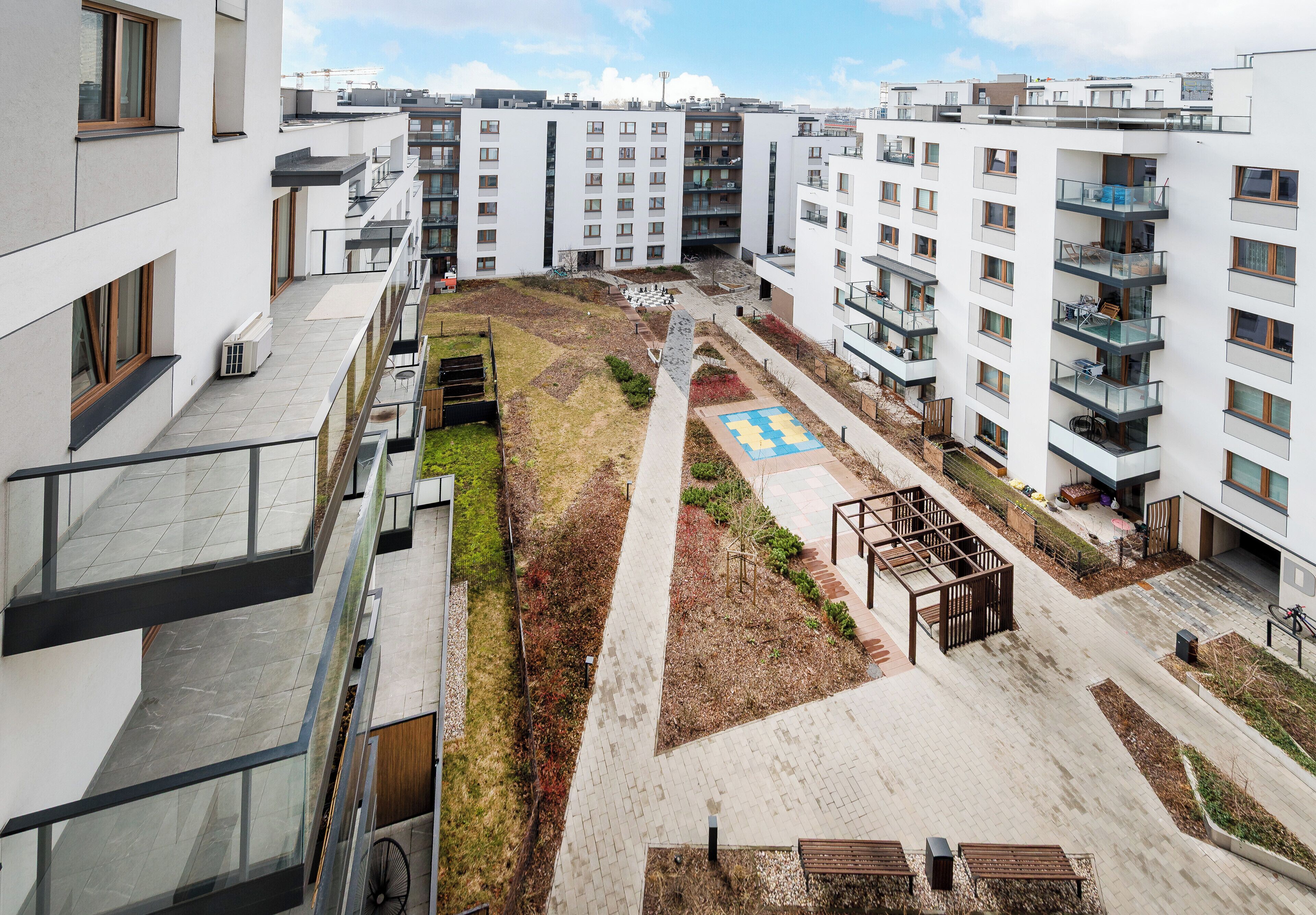 A multi-story residential building with balconies, a central courtyard with a playground, and a bike rack.