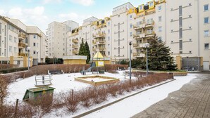 A residential building with multiple balconies, a playground, and a snow-covered ground. - Metro Ursynów Homely Apartment (Warszawa)