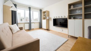 A modern living room with a sofa, a flat-screen TV, and built-in shelving. - Metro Ursynów Homely Apartment (Warszawa)