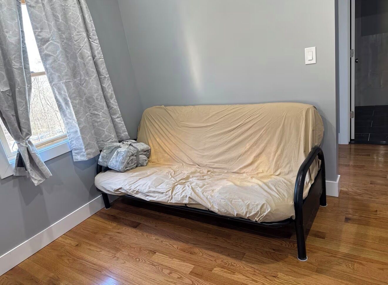 Ein Zimmer mit einem Bett, einem Vorhangfenster und einer Tür.