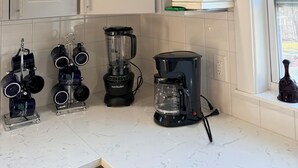 A kitchen with white cabinets, a coffee maker, a blender, and a kettle.
