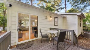 Eine kleine Hütte mit einer Veranda, einer Glasschiebetür zu einer Küchenzeile und einem kleinen Tisch mit Stühlen.