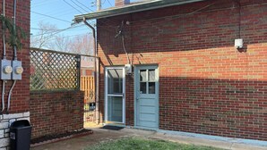 Una casa in mattoni con una porta d'ingresso, un piccolo giardino antistante e un'auto garage visibile.