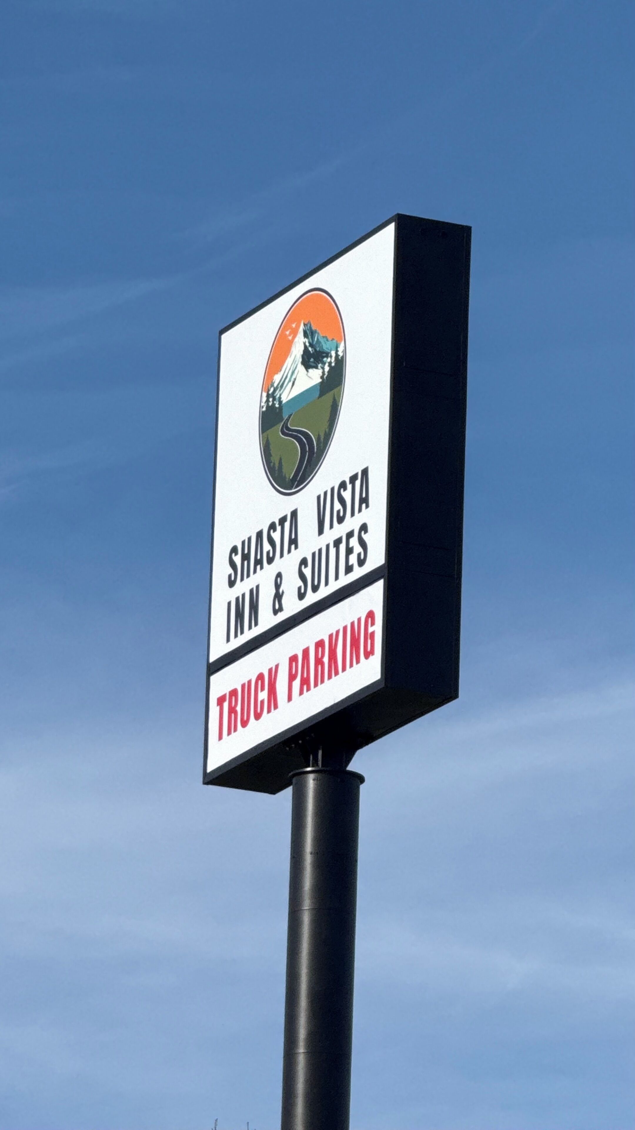 A sign for Shasta Vista Inn & Suites with a mountain logo and mentions truck parking.