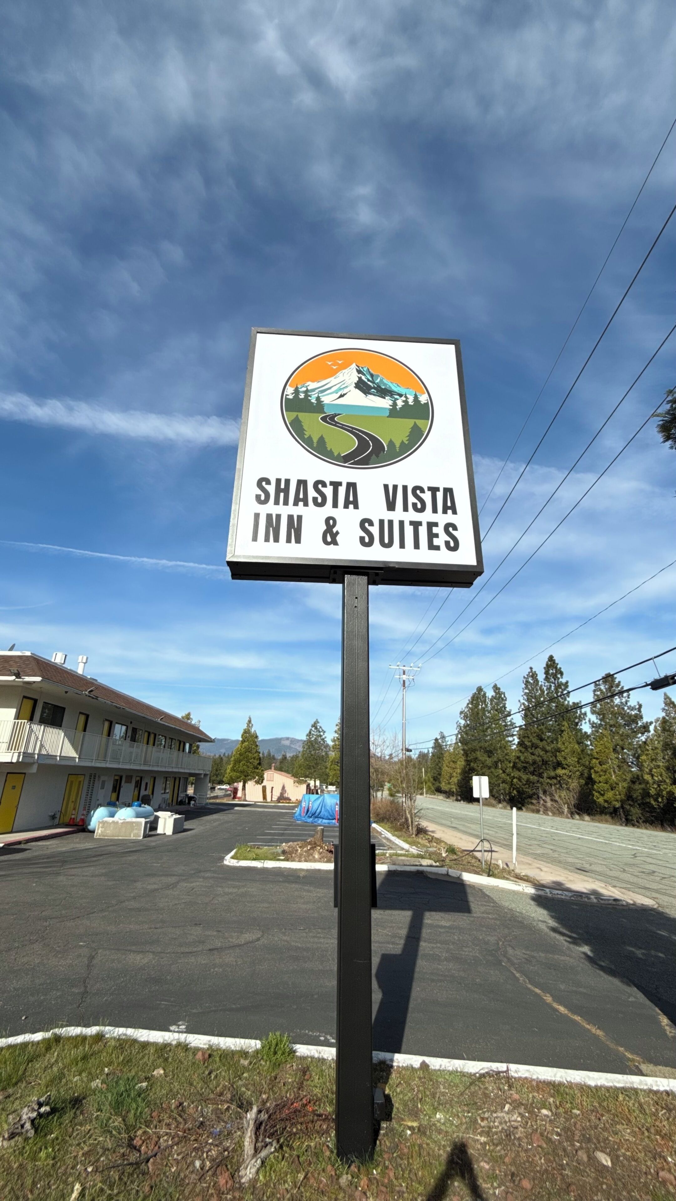 A sign for Shasta Vista Inn & Suites with a mountain and road illustration.