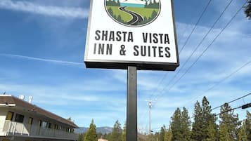 A sign for Shasta Vista Inn & Suites with a mountain and road illustration.