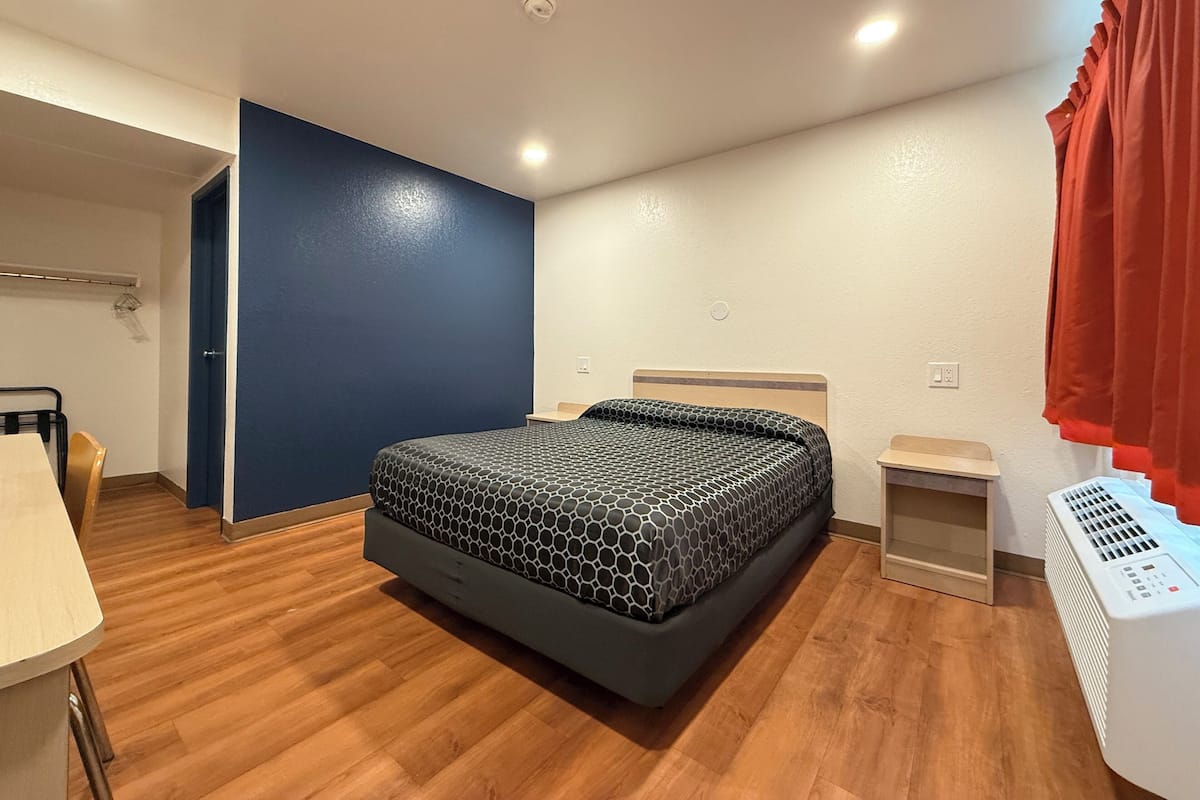 A bedroom with a bed, a desk, a chair, a heater, and a wardrobe.