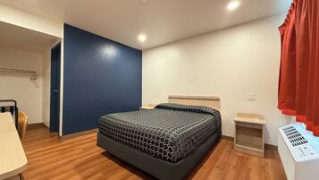 Un dormitorio con cama, escritorio, silla, calentador y armario.