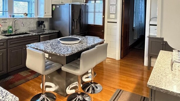 A modern kitchen with granite countertops, stainless steel appliances, and a central island with bar stools.