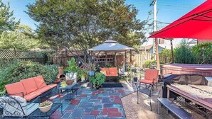A patio area with outdoor furniture, a covered seating area, and a brick floor.