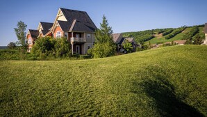 A large house with a balcony, surrounded by a grassy field and trees. - 3 Peaks at Blue Mountains, your luxury staycation! (The Blue Mountains)