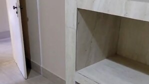 Um quarto com porta branca, estante branca e chão de azulejos.