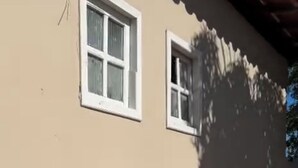 Um edifício bege com duas janelas e uma sombra projetada na parede.
