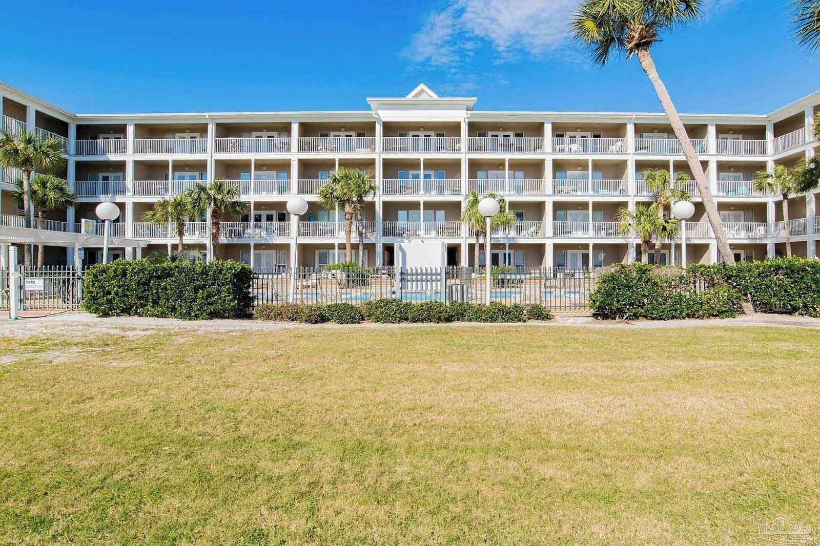 Un hôtel à plusieurs étages doté de balcons, d’une piscine et de palmiers.