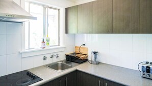 Una cocina moderna con un lavamanos de acero inoxidable, una estufa y armarios de madera oscura.