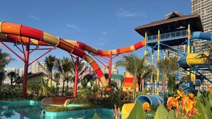 Ein Wasserpark mit mehreren Wasserrutschen und einem Poolbereich, umgeben von tropischer Vegetation.