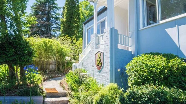 Une maison bleue avec une façade en pierre et une plaque numérotée.