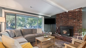 Ein Wohnzimmer mit Ecksofa, Couchtisch, Kamin und einem an der Wand befestigten Fernseher.