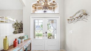 A foyer with a wooden bench, a chandelier, and a decorative wall piece. - Gulf Access, Heated Pool, Bikes- Coastal Breeze - Roelens Vacations (Cape Coral)