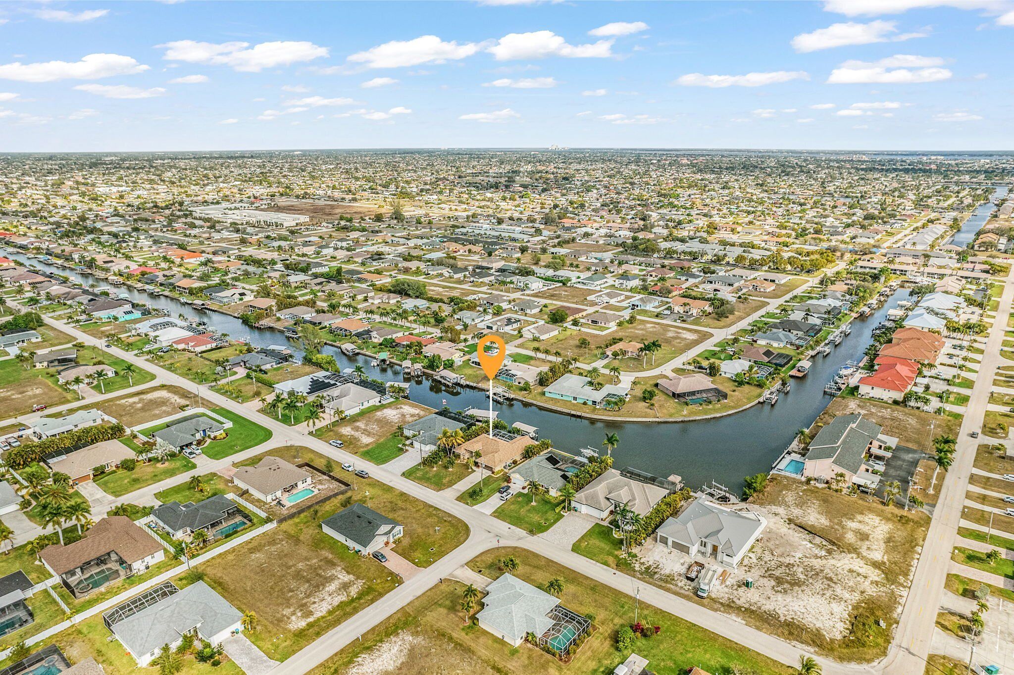 An aerial view of a residential area with a river running through it, surrounded by houses and greenery.