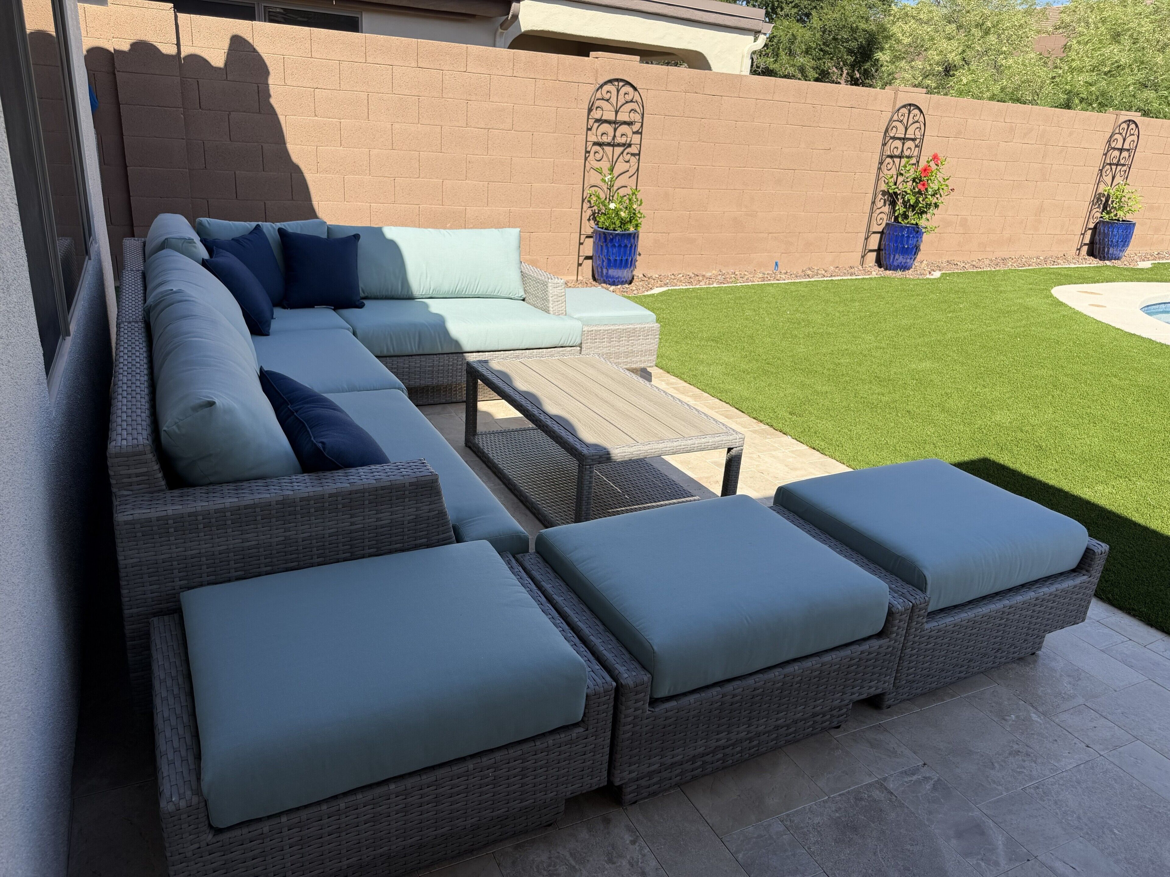 A patio with a sectional sofa, two side tables, and a small wooden table.