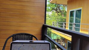 Un ordinateur portable est posé sur une table, l’écran affiche une carte, une canette de bière se trouve à proximité, et on aperçoit un bâtiment avec un balcon.