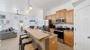 A modern kitchen with granite countertops, stainless steel appliances, and wooden cabinets. - Seaside Oasis - Sleeps 17 (Panama City)