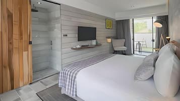 Ein modernes Hotelzimmer mit einem großen Bett, einem Fernseher, einer Dusche und einem Balkon mit Aussicht.