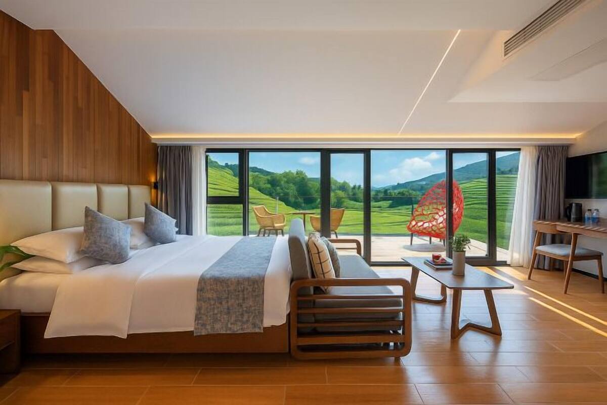 Una habitación de hotel moderna con una cama grande, un área de descanso con vistas y un escritorio.