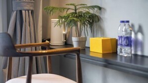 A chair, a potted plant, a yellow box, and water bottles on a counter. - Yashi Mountain Stream · Children's Swimming Pool Designer Parent Child Vacation Scenic Stay (Hangzhou)