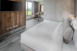 Et moderne hotelværelse med en stor seng, et skrivebord og et tv ophængt på væggen.