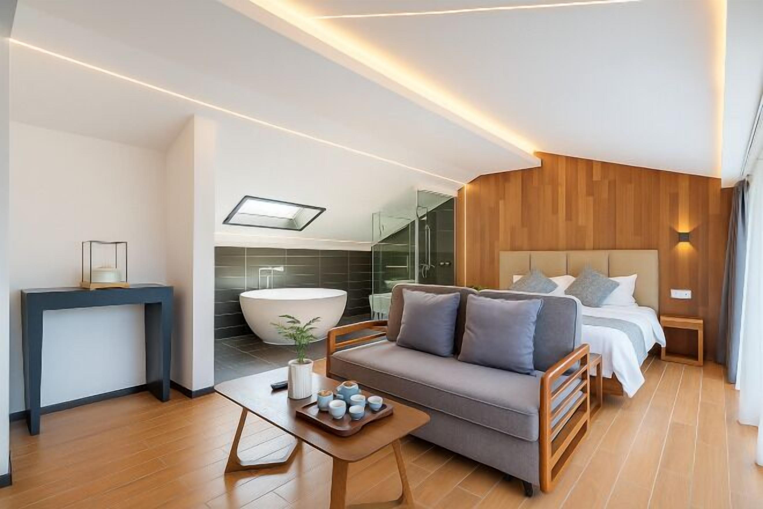 Quarto de hotel moderno com sofá, mesa de cabeceira e uma cama grande.