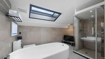 A modern bathroom with a freestanding bathtub, a glass-enclosed shower, and a skylight above.