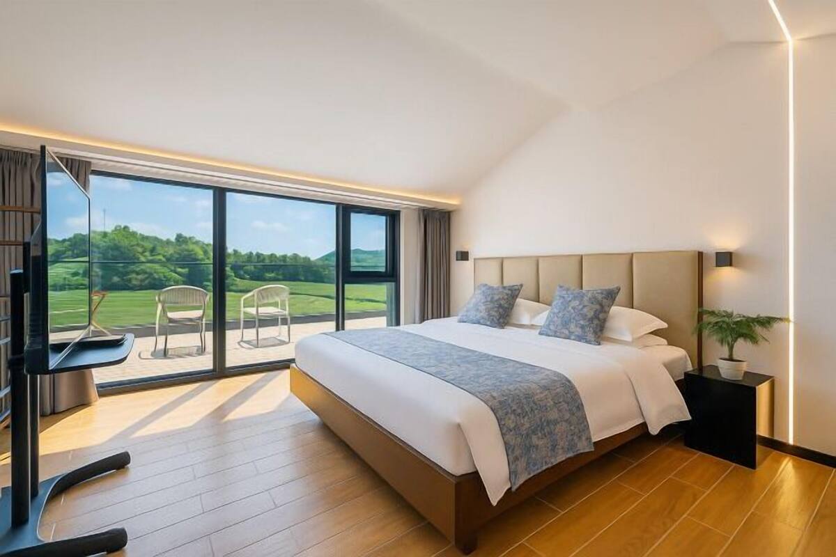 Un dormitorio moderno con una cama grande, un televisor y un balcón con sillas.