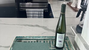 A kitchen counter with a bottle of wine, a tray with a towel, and a sign indicating a WiFi network. - Cayuga Lake Holiday House - Waterfront w/ Sunset Views (Ledyard)