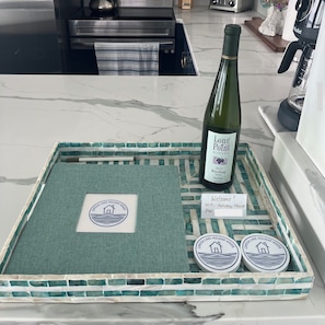 A kitchen counter with a bottle of wine, a tray with a towel, and a sign indicating a WiFi network. - Cayuga Lake Holiday House - Waterfront w/ Sunset Views (Ledyard)