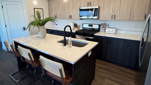 A modern kitchen with a central island, stainless steel appliances, and pendant lighting. - Heber Valley Condo-Pickleball-Tesla Charger (Heber City)