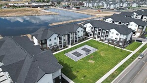 A residential area with modern apartment buildings, a central green space, and a body of water in the background. - Heber Valley Condo-Pickleball-Tesla Charger (Heber City)