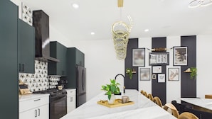 A modern kitchen with dark cabinets, a central island, and a dining area with chairs.