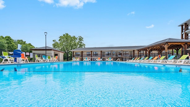 Ein Schwimmbecken mit Liegestühlen und ein Gebäude mit mehreren Fenstern im Hintergrund.