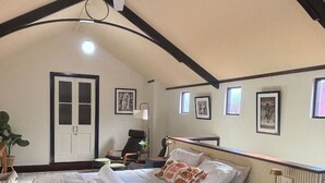 A bedroom with a large bed, a desk, and a chair. There is a door and a window. - Pawfect Retreat – Luxe Dog Stay, Walk to Town (Bridgetown)